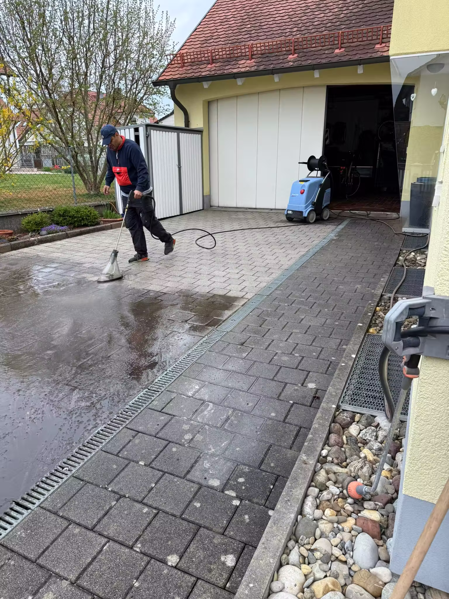 Garageneinfahrt während der Steinreinigung mit Flächenreiniger